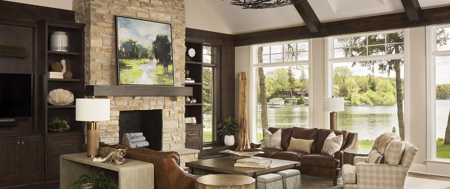 stone fireplace,. great room, leather sofas, cocktail table, side table, book cases, rug, console table, table lamp, arm chair, ottomans, pillows, accessories, lake view, chandelier