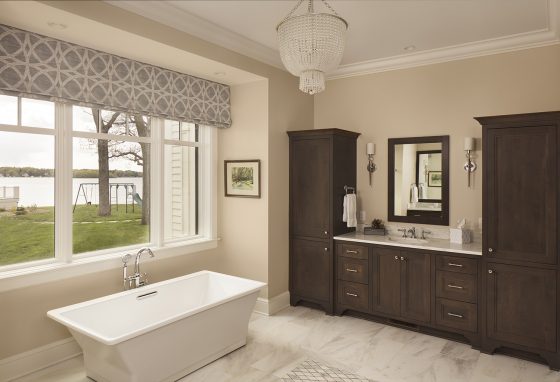 master bath, freestanding tub, rectangular tub, stained wood cabinetry, vanity, beaded cahndelier, window treatment, geometric fabric, sconces, mirror, marble floor
