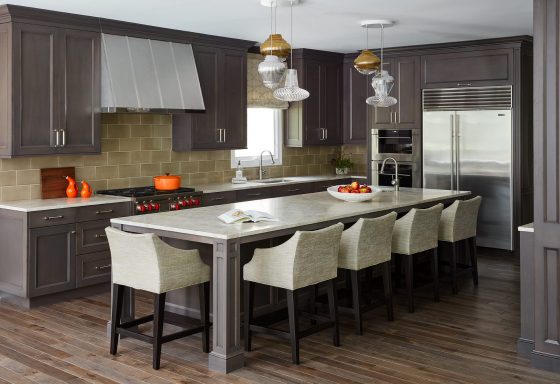stained wood kitchen with island, counter stools, range hood, pendant lights