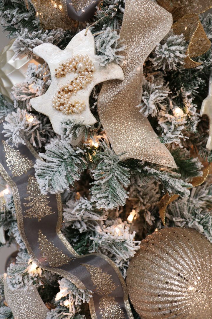 Closeup of Christmas tree ornament, fleur-de-lis ornament, flocked branches, ribbon