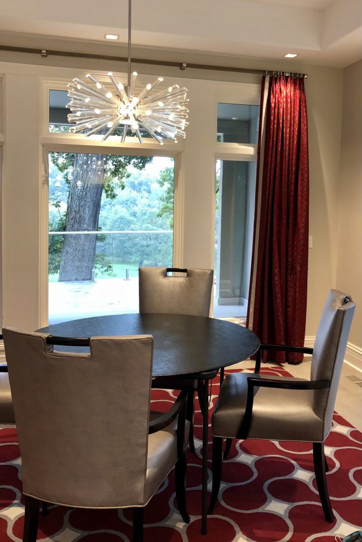 breakfast room, red rug, red window panels, round table, chandelier