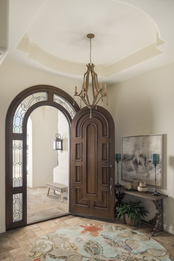 front entry, botanical rug, arched doorway, chandelier, chest, wall art, accessories