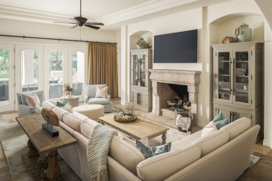 living room, fire place, sectional sofa, arm chairs, wall-mounted TV, cocktail table, sofa table, pillows, throw, accessories, ceiling fan, built-in cabinets 