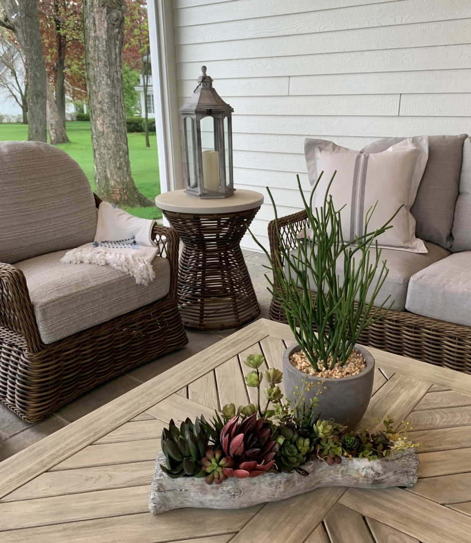 lake home, wisconsin, covered porch, wood table, potted succulents, wicker arm cahir, wicker sofa, wicker side table, grey cushions, lantern, pillow, throw